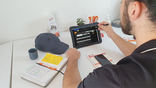Diagnostiqueur immobilier bc2E à Lille saisissant un diagnostic immobilier sur tablette, au bureau, avec carnet de notes et documents de diagnostics immobiliers obligatoires.
